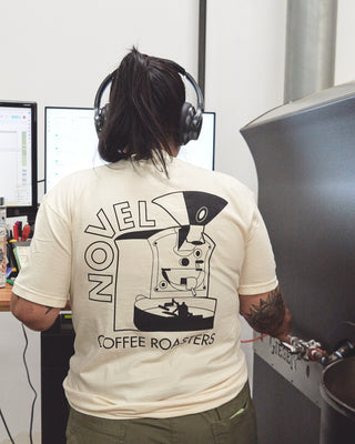 Woman wearing headphones at coffee roaster wearing cream tee shirt