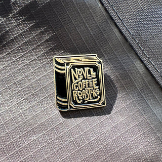 Enamel pin shaped as a book pinned to a canvas material.
